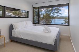 a bedroom with a bed with a teddy bear on it at Seashells Lakeside Holiday Perfection in Smiths Lake