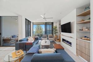 a living room with blue couches and a tv at Kings Beach Oceanfront Oasis in Caloundra