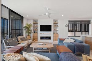 a living room with blue furniture and a tv at Kings Beach Oceanfront Oasis in Caloundra