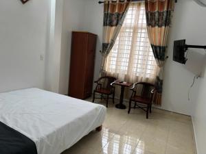 a bedroom with a bed and chairs and a window at Nhà nghỉ thảo chung in Kỳ Lừa