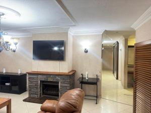 a living room with a fireplace and a television on the wall at The Cozy Corner House in Durban