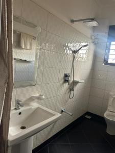 a white bathroom with a sink and a shower at Aape Motel Kamuli in Kamuli