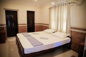 a bedroom with a bed with white sheets and a window at Hotel Jebasakthy in Kanyakumari