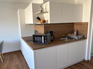 a kitchen with white cabinets and a microwave on a counter at Appartementhaus Silke in Bad Füssing +14 photos