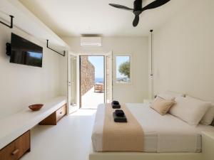a white bedroom with a bed and a tv at Villa Venti Private Pool Retreat, Mykonos in Agios Ioannis Mykonos