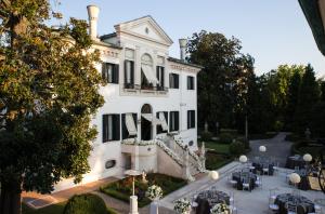 une maison blanche avec des tables et des chaises devant elle dans l'établissement Relais et Châteaux Hotel Villa Franceschi, à Mira