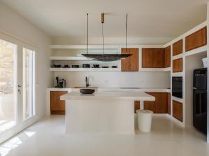 a kitchen with wooden cabinets and a white counter top at Villa Venti Private Pool Retreat, Mykonos in Agios Ioannis Mykonos