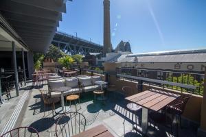 a patio with tables and chairs on a roof at Mercantile Hotel in Sydney