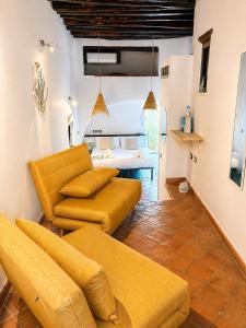 a living room with yellow furniture and a bedroom at Spinuzza Boutique Guesthouse Cefalù, Sicily in Cefalù