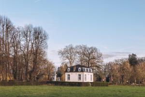 a white house in a field with trees at Portierswoning Vaeshartelt in Maastricht