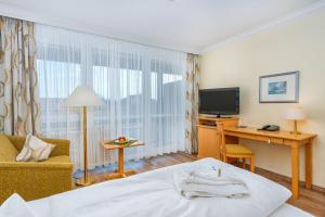 a hotel room with a bed and a desk and a television at Hotel Bayerischer Hof in Bad Füssing