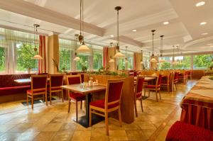 a restaurant with tables and chairs and windows at Hotel Bayerischer Hof in Bad Füssing