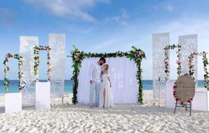 a bride and groom standing under an arch on the beach at Ukulhas Villa Hotel & Spa in Ukulhas