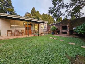 a backyard of a house with a grass yard at Leopards Tree Garden Cottage in Greytown