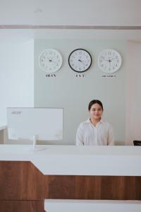 a man standing in front of a counter with clocks on the wall at Regal Havens in Jorhat