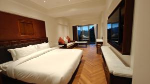 a bedroom with a large white bed and a window at Hotel Vishnu Palace in Mussoorie