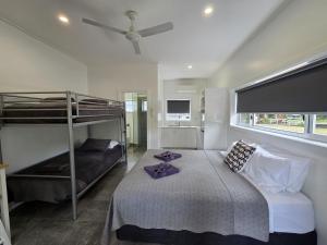 a bedroom with two bunk beds and a ceiling fan at Peninsula Caravan Park Cooktown in Cooktown