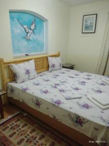 a bedroom with a bed with a bird painting on the wall at Casa de vacanta ,,Puiu & Nelly,, in Sulina