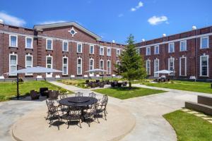 a courtyard with a table and chairs in front of a brick building at Academy by Ambassadori in Kachretʼi