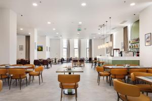 a restaurant with tables and chairs in a room at Academy by Ambassadori in Kachretʼi