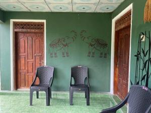 three chairs in front of a green wall with elephants on the wall at Ceylona Homestay in Kurunegala