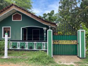 a house with a green fence and a gate at Ceylona Homestay in Kurunegala