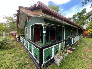 a small green house with a person standing in front of it at Ceylona Homestay in Kurunegala