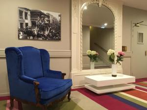 a blue chair in a room with a table and a mirror at Hôtel Le Royal Promenade des Anglais in Nice