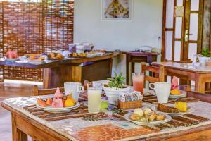 a table with plates of food and glasses of milk at Pousada Vila dos Passaros in Itacaré