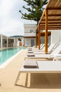 a pool with white lounge chairs and a swimming pool at Aspronissos Hotel in Skiathos