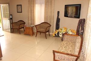 a living room with chairs and a tv on the wall at Hotel Residence Flamani in Lomé