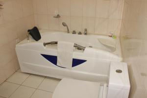 a bathroom with a white tub and a toilet at Hotel Residence Flamani in Lomé
