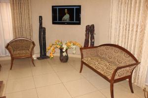 a living room with two chairs and a vase with flowers at Hotel Residence Flamani in Lomé