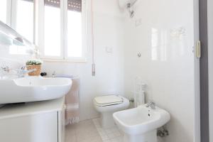 a white bathroom with a toilet and a sink at Villa Anna in Torre Santa Sabina