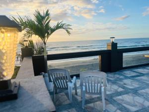 two white chairs sitting on a patio overlooking the ocean at Beachfront Studio with Cozy and Spacious Balcony in Baling