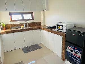 a kitchen with white cabinets and a black refrigerator at Beachfront Studio with Cozy and Spacious Balcony in Baling
