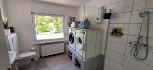 a bathroom with a washing machine and a window at Ferienhaus an der Ölmühle in Heusweiler