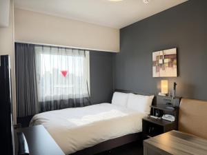 a hotel room with a bed and a window at Hotel Route-Inn Yanagawa Ekimae in Yanagawa