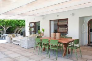 a patio with a wooden table and green chairs at Rijke Rust, Living the Lagoon Life in Langebaan