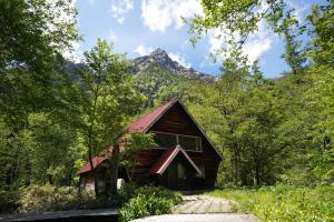 a cabin in the woods with a mountain in the background at Yamano Hidaya in Matsumoto