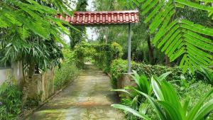 a path in a garden with a red roof at PINE-APPALE Riverside Resort in Ấp Kế Mỹ