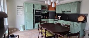 a kitchen with green cabinets and a table with chairs at Les Preuses, un Grand Cru de Chablis avec jacuzzi in Fontenay-près-Chablis +7 photos