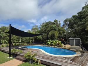 a swimming pool with a canopy over a wooden deck at Peninsula Caravan Park Cooktown in Cooktown