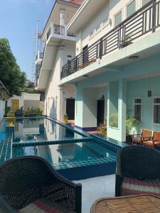 ein Schwimmbecken mit zwei Stühlen und ein Gebäude in der Unterkunft Saba Lua Siem Reap in Siem Reap