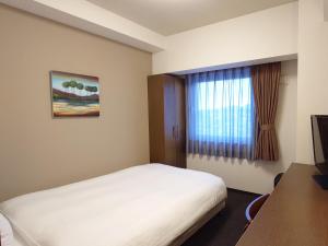 a hotel room with a bed and a window at Hotel Route-Inn Yurihonjo in Yurihonjo