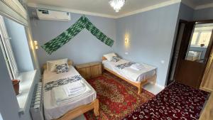 a small room with two beds and a window at Khiva Mahliyo in Khiva