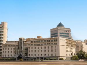 a large white building with a tower on top of it at Mövenpick Hotel & Apartments Bur Dubai in Dubai