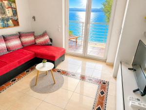 a living room with a red couch and a view of the ocean at Apartman Nina Selce in Selce