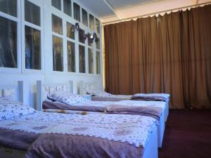 two beds in a room with windows and curtains at Ali guest house Samarkand in Aman-Kutan