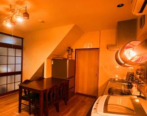 a kitchen with a table and a sink and a refrigerator at オリーブママのヤド 凪 バーベキュー機材レンタル可 in Shodoshima